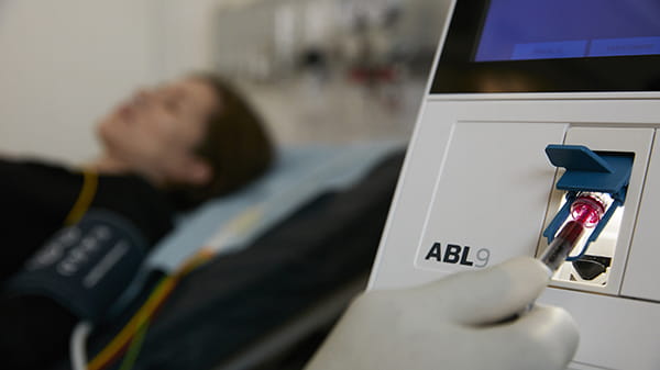 Close up of hand inserting a sample into the ABL9 blood gas analyzer